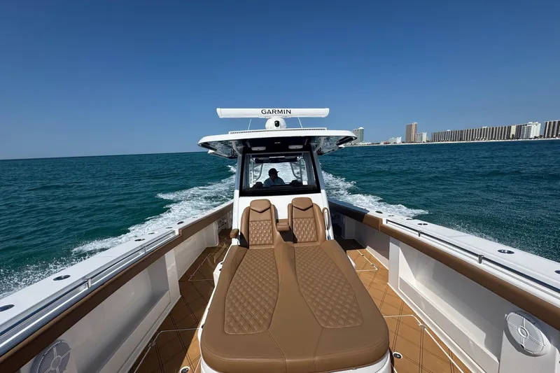  Yacht Photos Pics 2024 Invincible 46 Catamaran cruising on open water with city skyline in background.