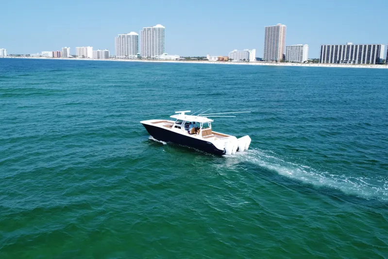  Yacht Photos Pics 2024 Invincible 46 Catamaran cruising on blue ocean near city skyline.