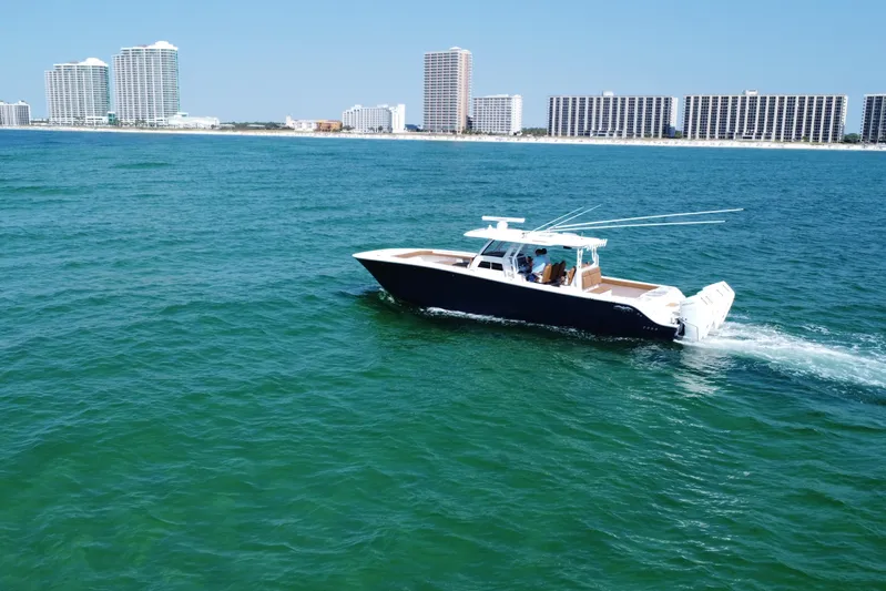  Yacht Photos Pics 2024 Invincible 46 Catamaran cruising on ocean with city skyline in background.