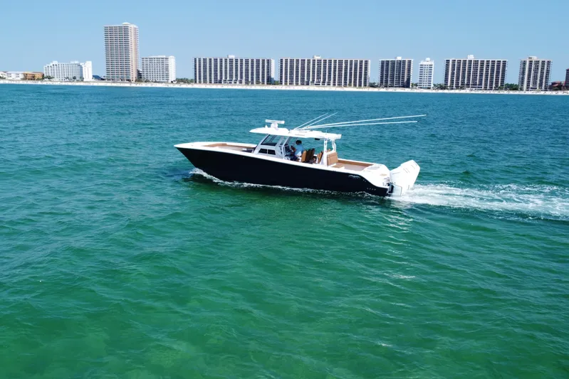  Yacht Photos Pics 2024 Invincible 46 Catamaran cruising on clear blue waters near a city skyline.