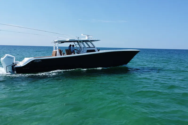  Yacht Photos Pics 2024 Invincible 46 Catamaran cruising on open sea under clear blue sky.