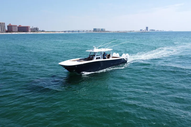  Yacht Photos Pics 2024 Invincible 46 Catamaran cruising on open water near coastal cityscape.