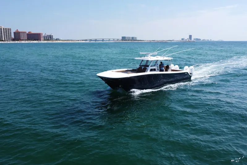  Yacht Photos Pics 2024 Invincible 46 Catamaran cruising on open water near coastal cityscape.