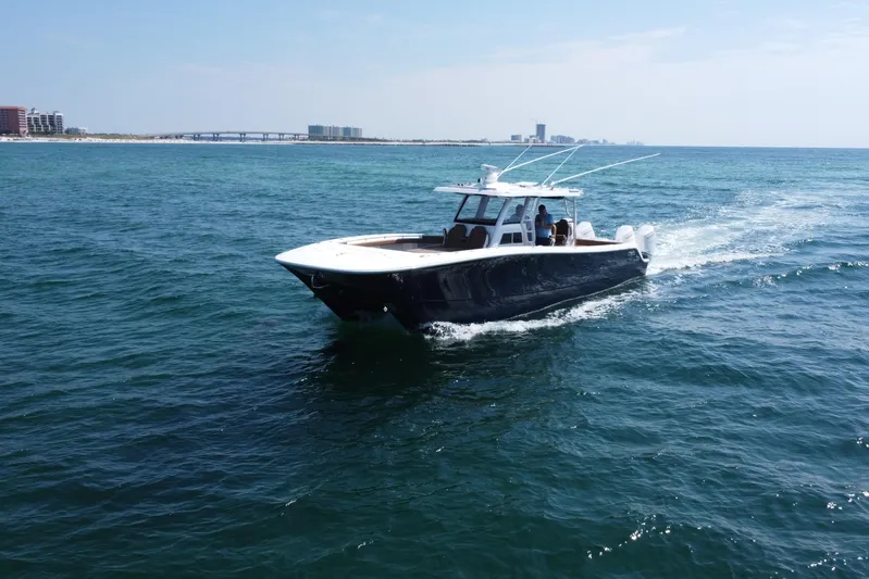  Yacht Photos Pics 2024 Invincible 46 Catamaran cruising on open water, with distant cityscape background.