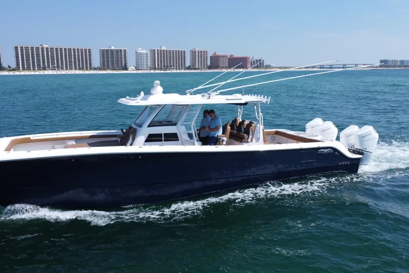  Yacht Photos Pics 2024 Invincible 46 Catamaran cruising on ocean near coastal cityscape.