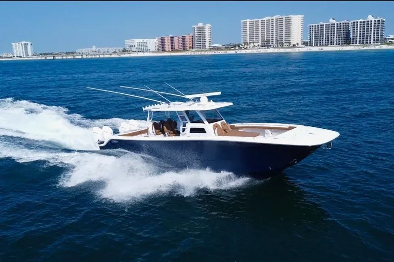  Yacht Photos Pics 2024 Invincible 46 Catamaran cruising on ocean near coastal city skyline.