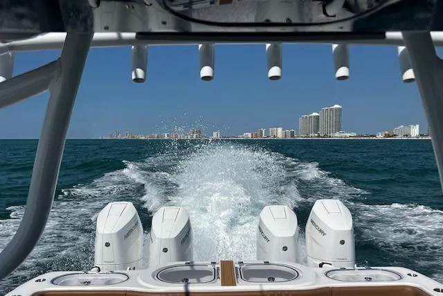  Yacht Photos Pics 2024 Invincible 46 Catamaran cruising on ocean, city skyline in background.