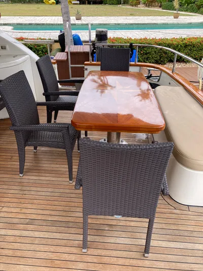 Dreamer Yacht Photos Pics Outdoor dining area on 2005 Azimut 80 Carat yacht with wicker chairs and wooden table.