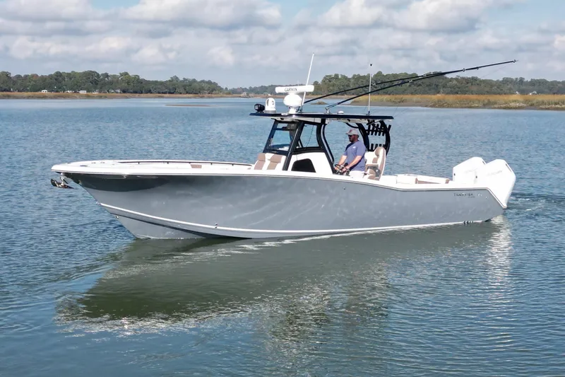  Yacht Photos Pics 2025 Tidewater 320 CC Adventure boat cruising on calm water under a partly cloudy sky.