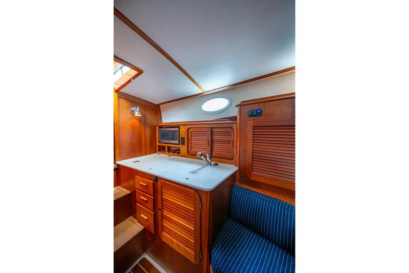 Ruckus Yacht Photos Pics 2017 Hinckley Picnic Boat 37 MKIII interior with wooden cabinetry and compact kitchen area.