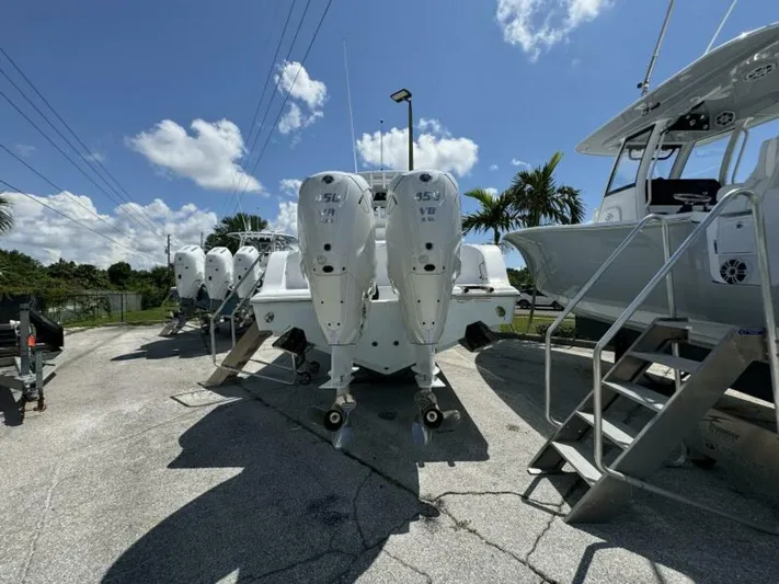  Yacht Photos Pics 2025 Sportsman 322 Open boat with powerful outboard engines, parked under a clear blue sky.