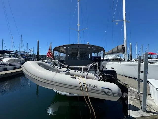 Simone Yacht Photos Pics Beneteau 490 sailboat, 2007 model, docked with inflatable dinghy, clear blue sky background.