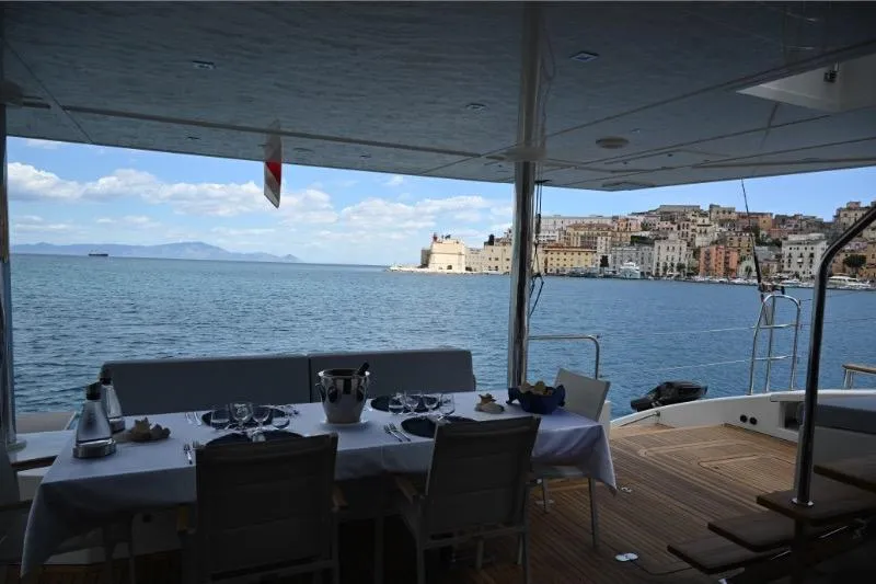  Yacht Photos Pics Luxury dining setup on 2015 Sunreef 74 yacht with scenic coastal view.
