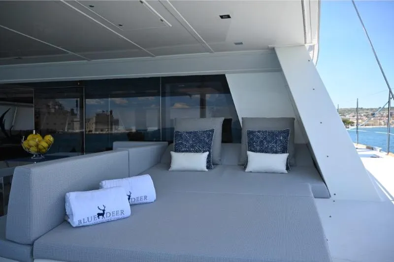  Yacht Photos Pics Luxurious Sunreef 74 yacht deck with plush seating, pillows, and towels, overlooking serene waters.