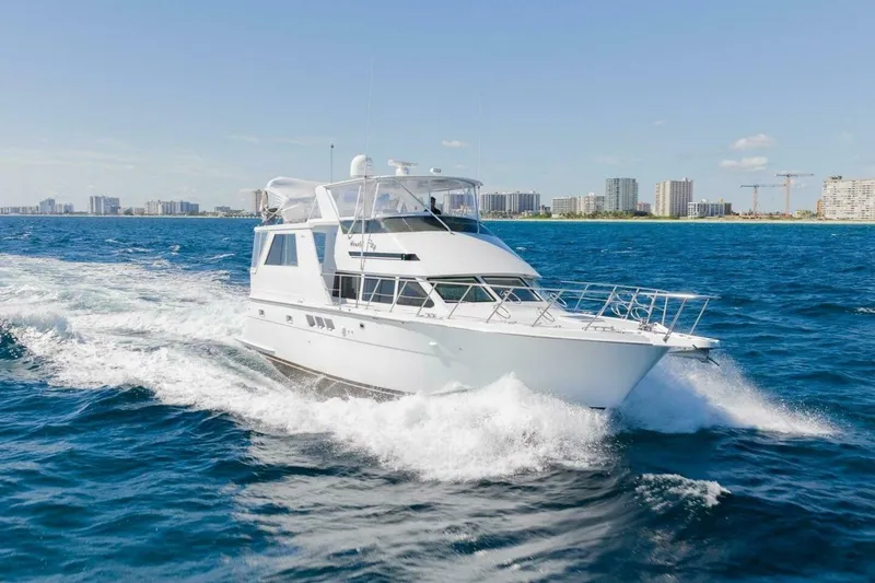 Hanalei Yacht Photos Pics 1999 Hatteras 52 Sport Deck Motor Yacht cruising on blue ocean near city skyline.
