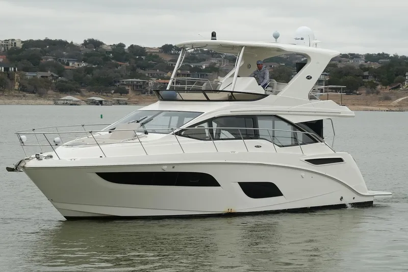 Smooth Yacht Photos Pics 2018 Sea Ray Fly 460 yacht cruising on a calm lake with scenic background.