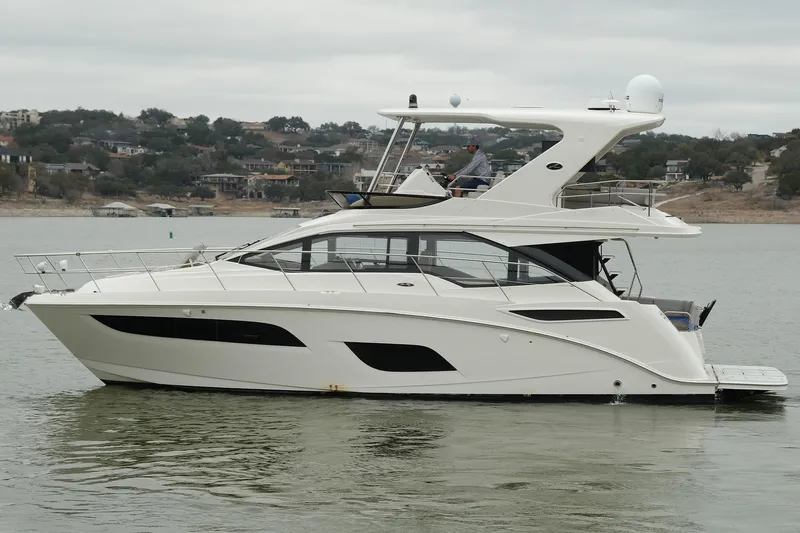 Smooth Yacht Photos Pics 2018 Sea Ray Fly 460 yacht on calm water, with scenic shoreline background.