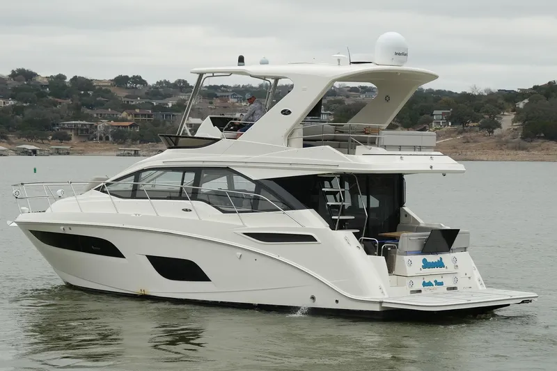 Smooth Yacht Photos Pics 2018 Sea Ray Fly 460 yacht cruising on a calm lake with scenic background.