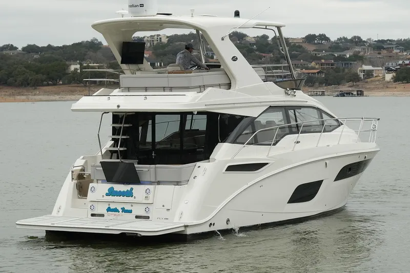 Smooth Yacht Photos Pics 2018 Sea Ray Fly 460 yacht cruising on a calm lake with scenic background.