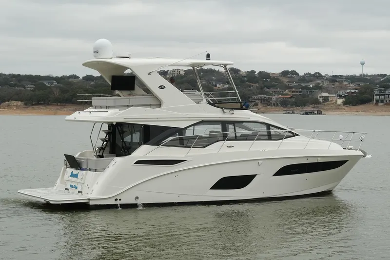 Smooth Yacht Photos Pics 2018 Sea Ray Fly 460 yacht cruising on a calm lake with scenic background.