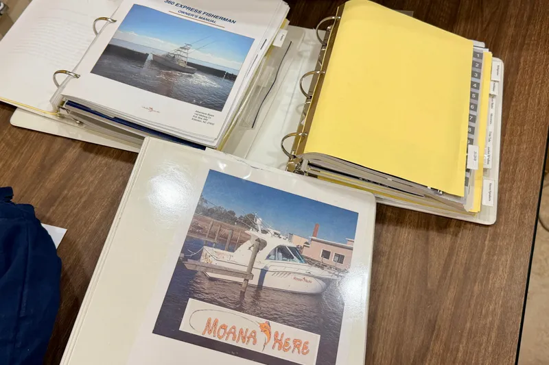 Moana Here Yacht Photos Pics Binders with manuals for 2015 Albemarle 360 Express Fisherman on a wooden table.