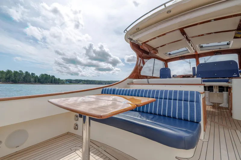 The Do-over Yacht Photos Pics 2024 Hinckley Picnic Boat 40 interior with blue seating and wooden table on a sunny day.