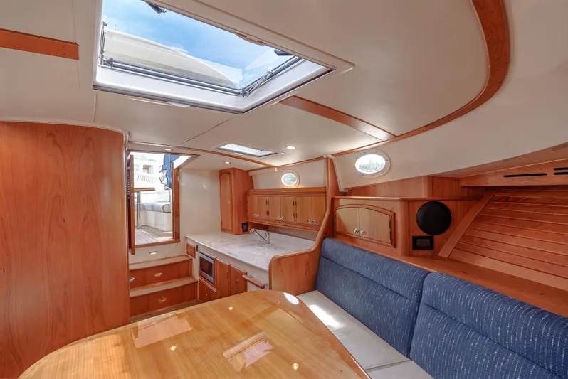 The Do-over Yacht Photos Pics 2024 Hinckley Picnic Boat 40 interior with skylight, wooden cabinetry, and blue seating.