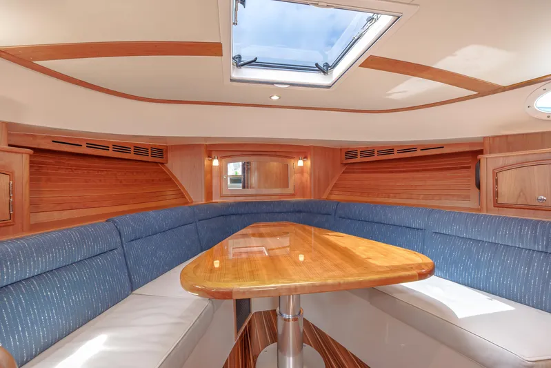 The Do-over Yacht Photos Pics 2024 Hinckley Picnic Boat 40 interior with skylight, wooden table, and blue seating.