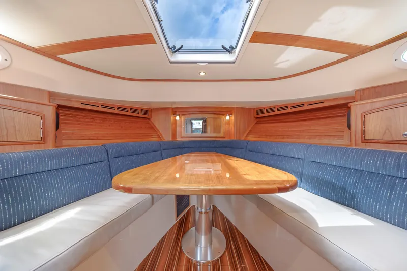 The Do-over Yacht Photos Pics 2024 Hinckley Picnic Boat 40 interior with skylight, wooden table, and blue seating.