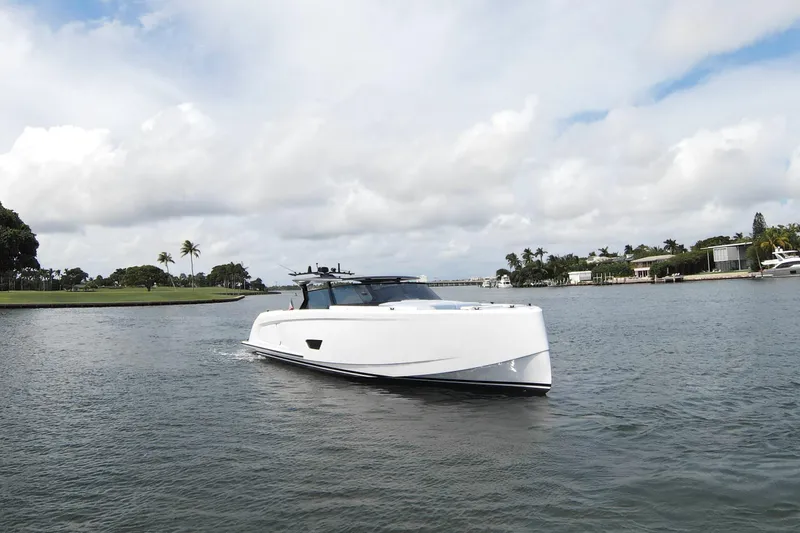 Shir Yacht Photos Pics 2024 Vanquish 58 yacht cruising on a scenic waterway under a cloudy sky.