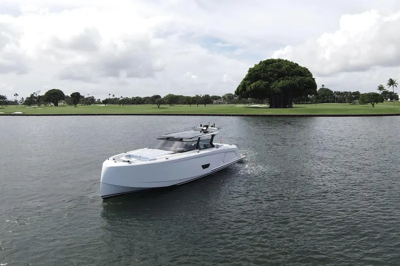 Shir Yacht Photos Pics 2024 Vanquish 58 yacht cruising on a serene lake with lush green surroundings.