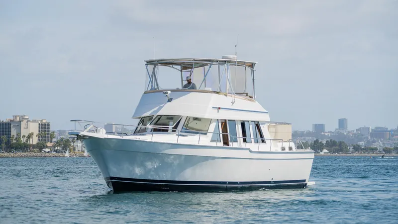 Temptation Yacht Photos Pics 2005 Mainship 43 Trawler Aft Cabin cruising on calm waters near city skyline.