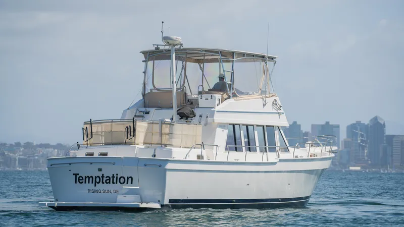Temptation Yacht Photos Pics 2005 Mainship 43 Trawler Aft Cabin cruising on water with city skyline in background.