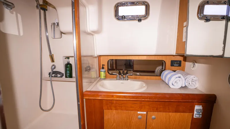 Temptation Yacht Photos Pics 2005 Mainship 43 Trawler Aft Cabin bathroom with shower, sink, and wooden cabinetry.