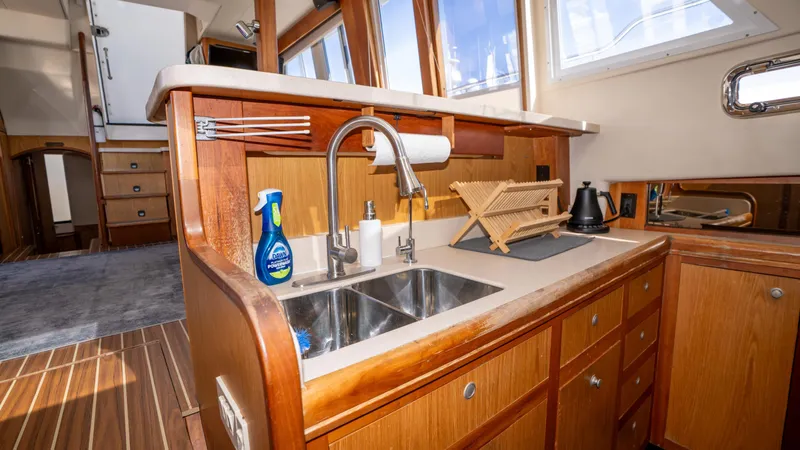 Temptation Yacht Photos Pics 2005 Mainship 43 Trawler Aft Cabin kitchen with wooden cabinetry and stainless steel sink.