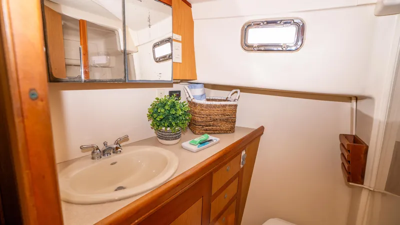 Temptation Yacht Photos Pics 2005 Mainship 43 Trawler Aft Cabin bathroom with sink, mirror, and porthole window.