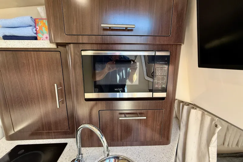 My Particular Harbor Yacht Photos Pics 2018 Regal 28 Express interior with microwave, wooden cabinetry, and modern kitchen amenities.