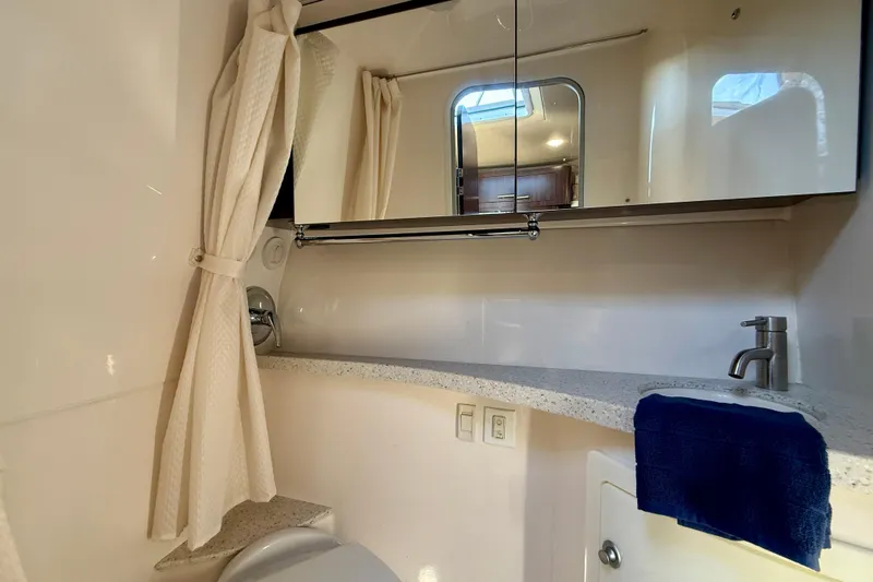 My Particular Harbor Yacht Photos Pics Bathroom interior of 2018 Regal 28 Express boat with mirror, sink, and shower curtain.