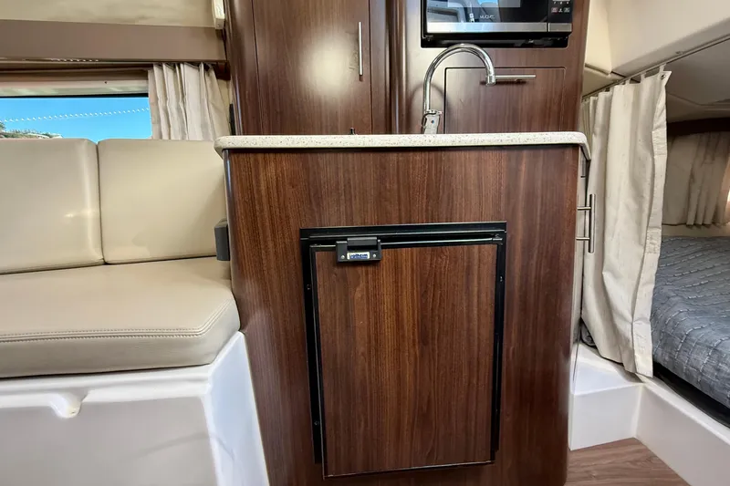 My Particular Harbor Yacht Photos Pics 2018 Regal 28 Express interior with kitchenette, featuring wood cabinetry and compact design.