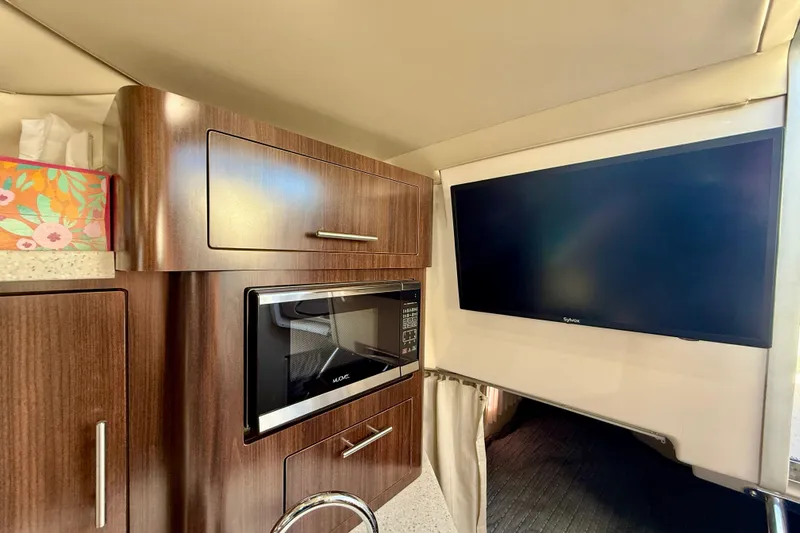 My Particular Harbor Yacht Photos Pics 2018 Regal 28 Express interior with microwave, cabinets, and wall-mounted TV.