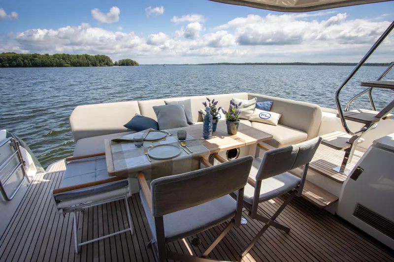  Yacht Photos Pics Luxurious 2021 Prestige 520 yacht deck with elegant dining setup and scenic water view.