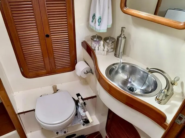 Circa Tempo Yacht Photos Pics Compact boat bathroom with wooden accents, featuring a toilet and stainless steel sink. Mason 44, 1991.