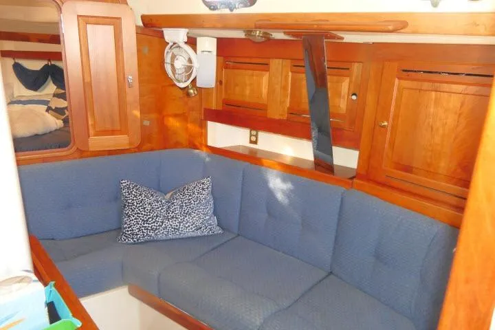 C Otter Yacht Photos Pics Cozy interior of 2002 Tartan 3700 sailboat with blue seating and wooden cabinetry.