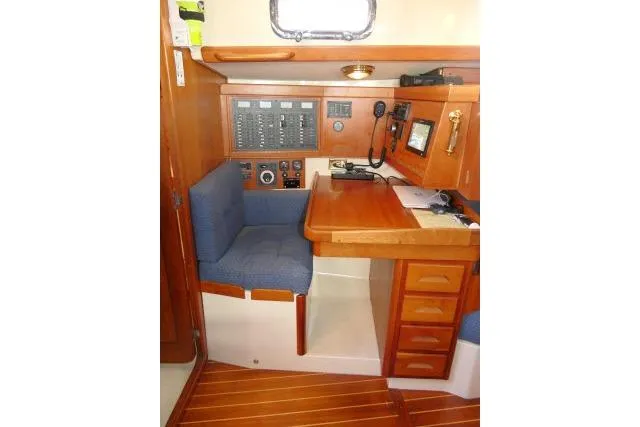 C Otter Yacht Photos Pics Navigation station in a 2002 Tartan 3700 sailboat with wood finish and blue seating.