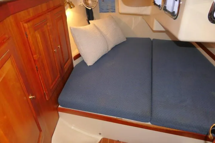 C Otter Yacht Photos Pics Cozy cabin interior of 2002 Tartan 3700 sailboat with blue bedding and wooden cabinetry.