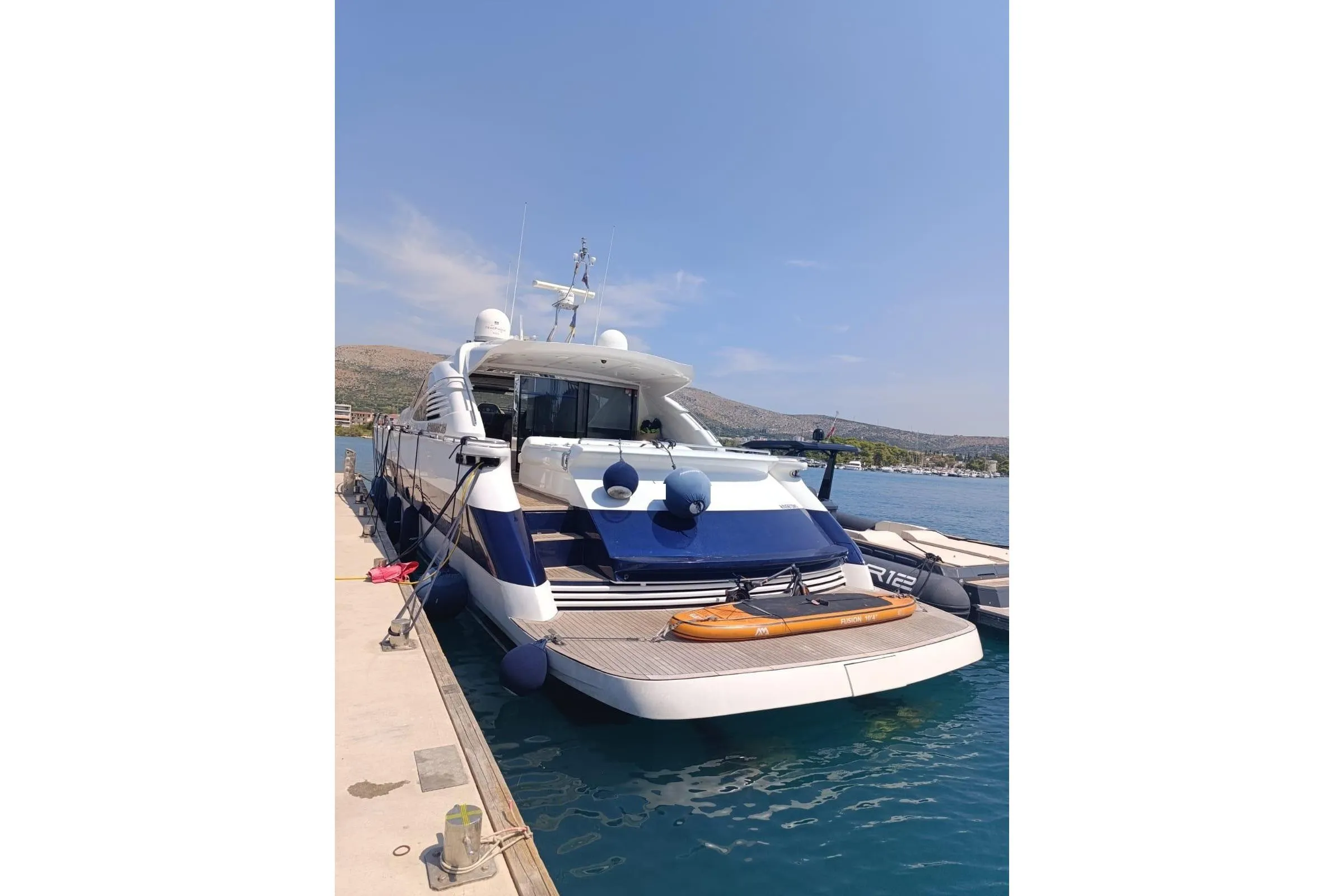 Luxury 2005 Pershing 76 yacht docked at marina under clear blue sky.