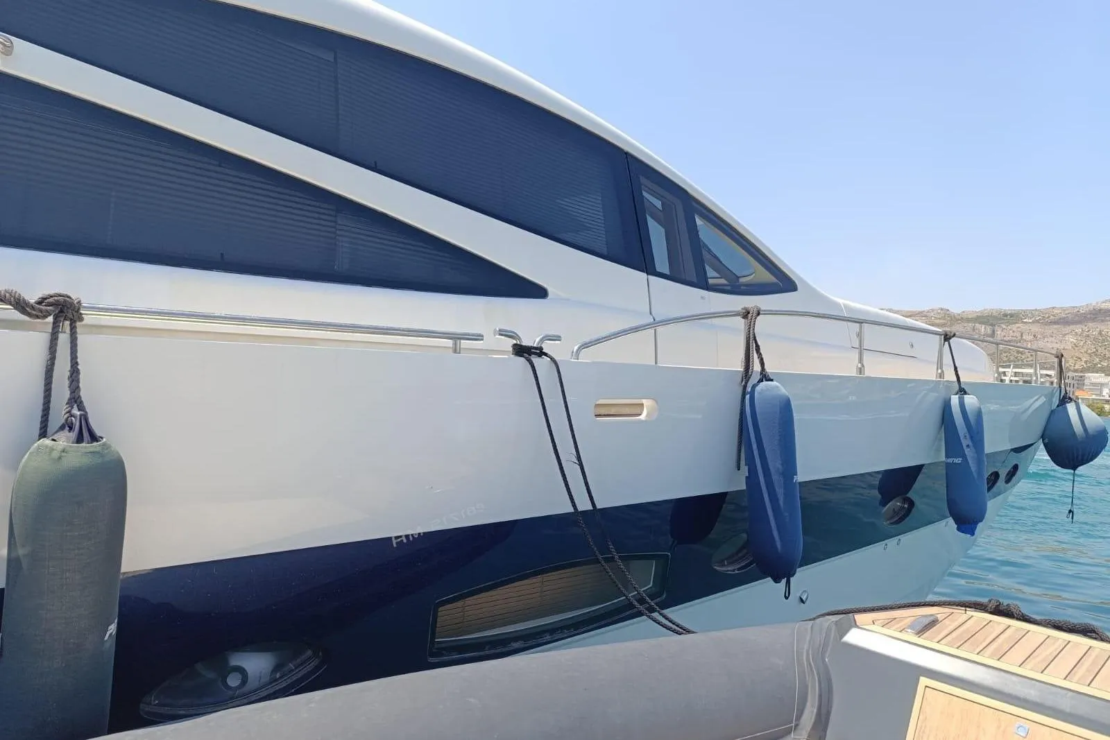 2005 Pershing 76 yacht docked with fenders, sleek design, sunny day.