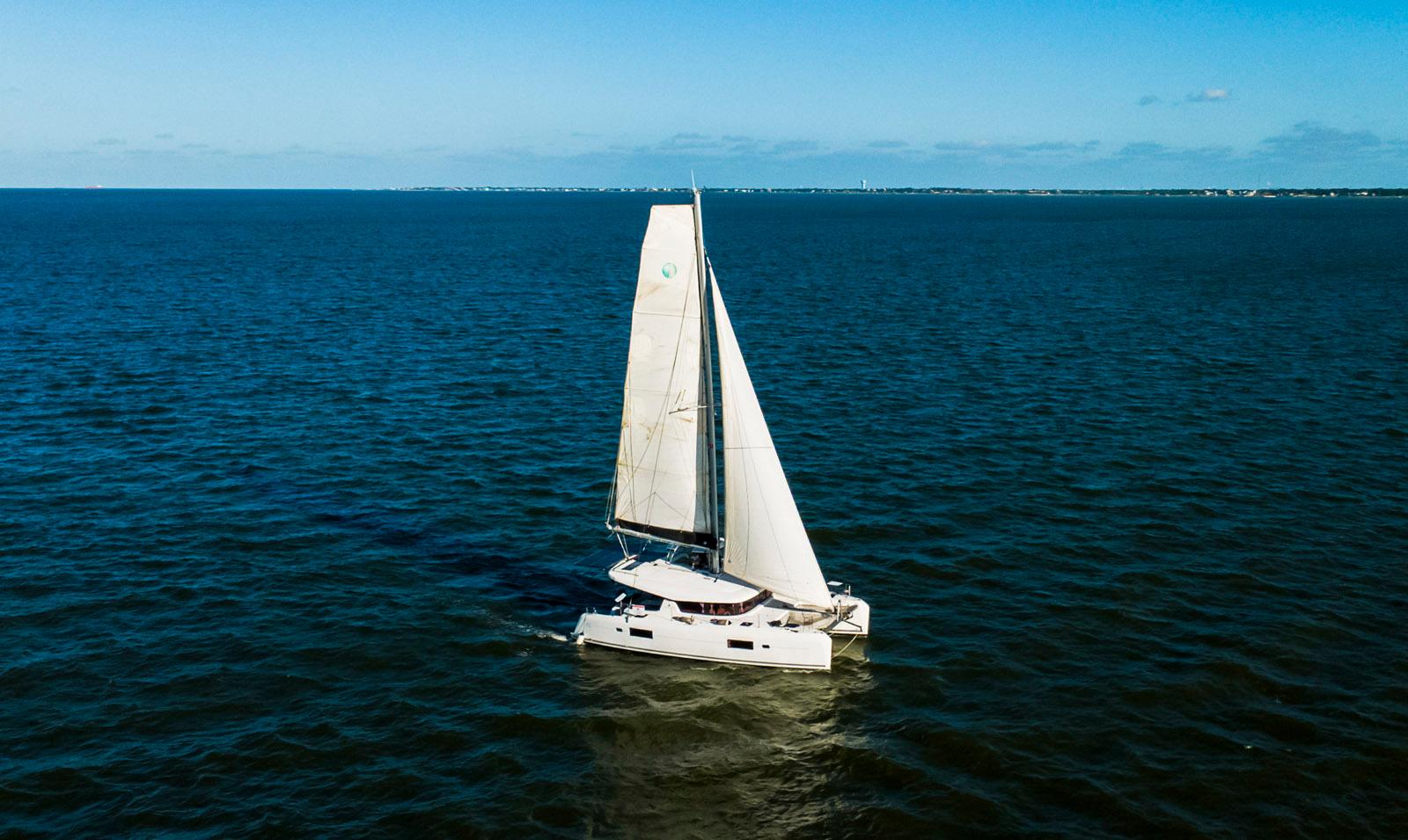 Sailing Lagoon 42 catamaran, 2017 model, gliding on open sea under clear blue sky.