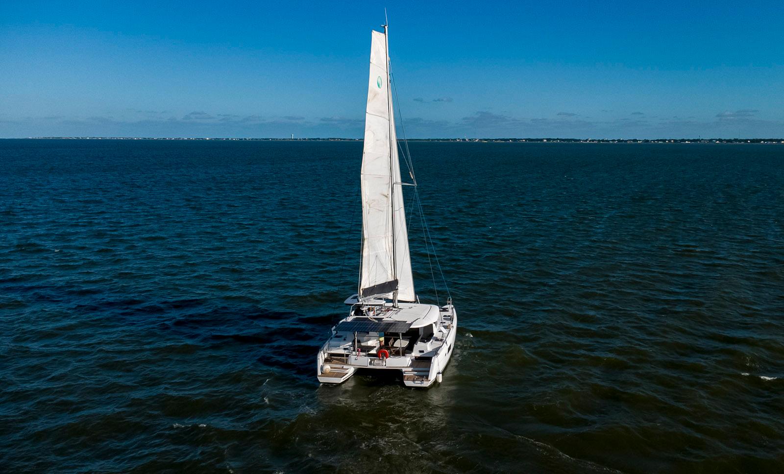 2017 Lagoon 42 catamaran sailing on open sea under clear blue sky.