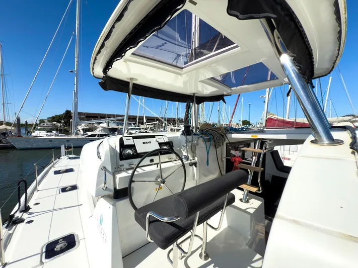 Blue Pearl Too Yacht Photos Pics 2017 Lagoon 42 catamaran cockpit with steering wheel, marina view, and clear blue sky.
